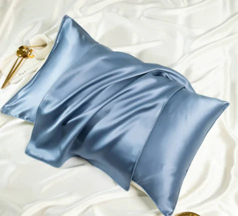 a blue pillow on a white bed with a pair of scissors