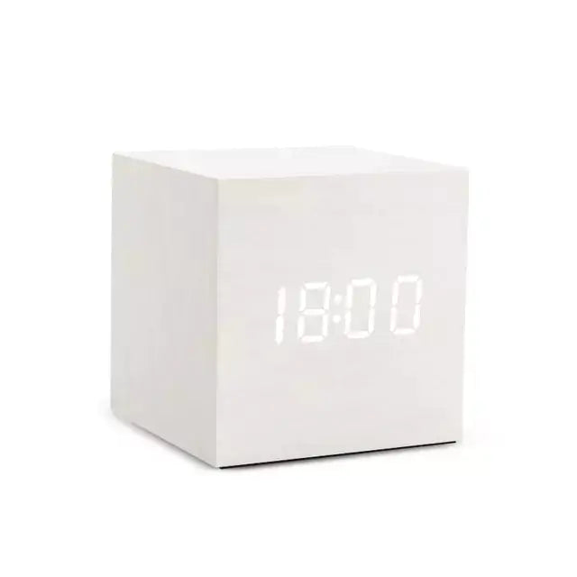 a white cube clock sitting on top of a table