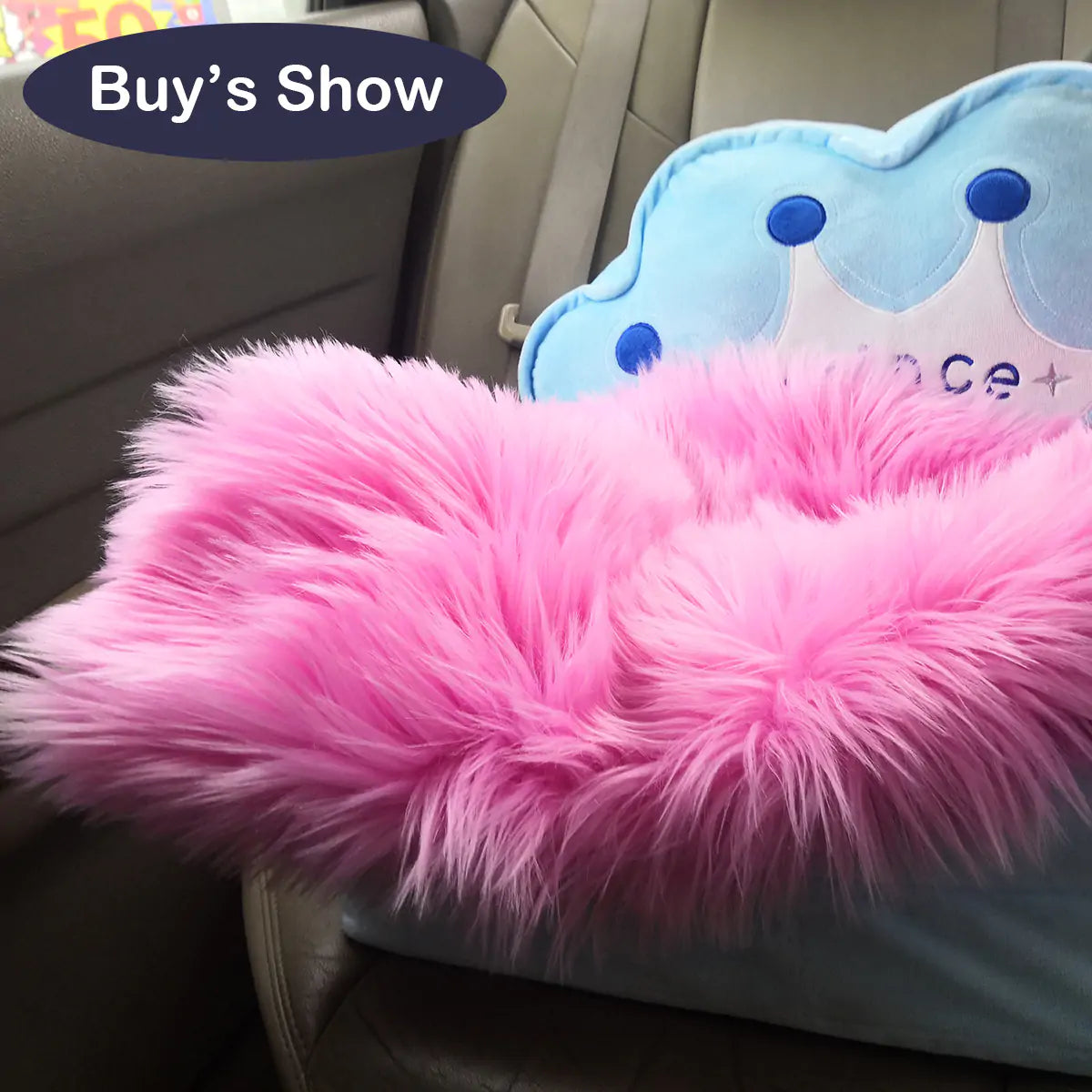 a pink furry pillow sitting on top of a car seat