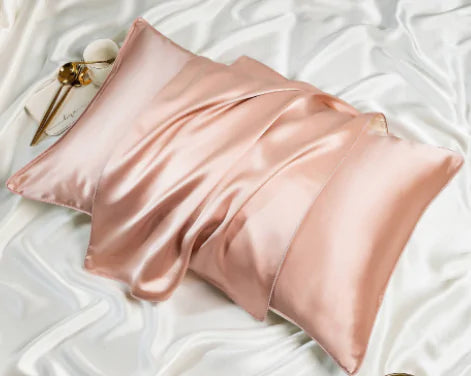 a pink satin pillow on a white bed