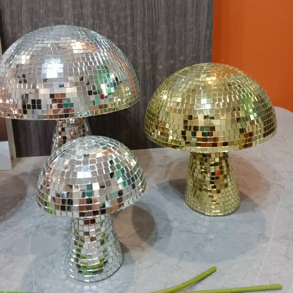 a table topped with three shiny disco ball covered mushrooms